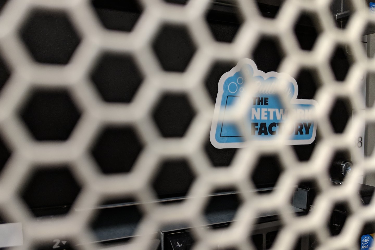 The perforated front of the image build server, a Network Factory sticker on the mesh, Xeon badges on the machines behind it.